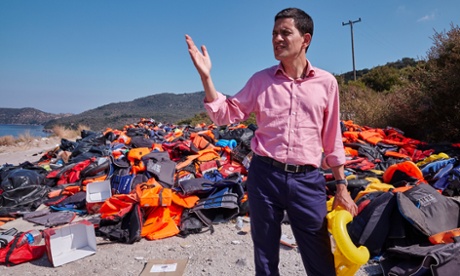 David Miliband in front of a pile of discarded life vests in Lesbos.