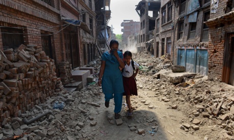 Nepalese schoolgirl walks with her mother past damaged buildings to school in Bhaktapur on the outskirts of Kathmandu on May 31, 2015.