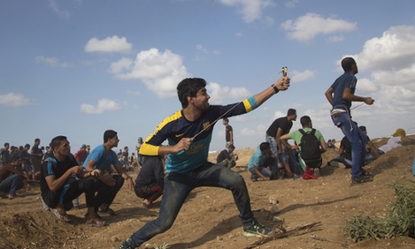 A Palestinian protester hurls stones at Israeli soldiers during clashes on the Israeli border with Eastern Gaza.