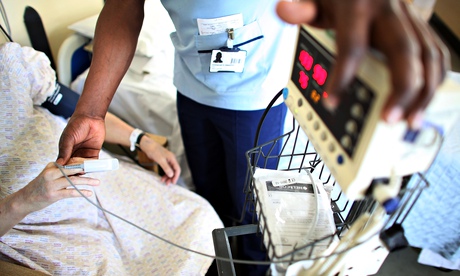 A nurse tends to a patient on a general ward