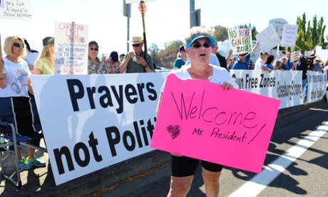 Dulcie Bagley, a supporter of Obama’s visit, walks past protesters lining the street in front of the Roseburg regional Airport on Friday.