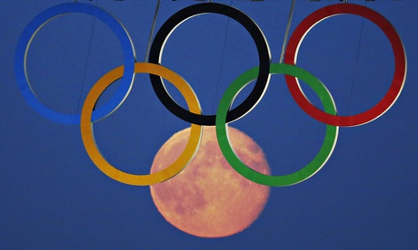 A full moon rises through the Olympic Rings