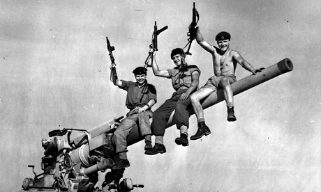 Three British soldiers sit on a gun captured from Egyptian forces during the Suez crisis