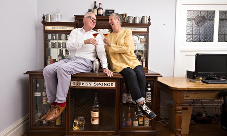 Henry and Judy Barnes sit on their cabinet, smiling and toasting each other with cocktails