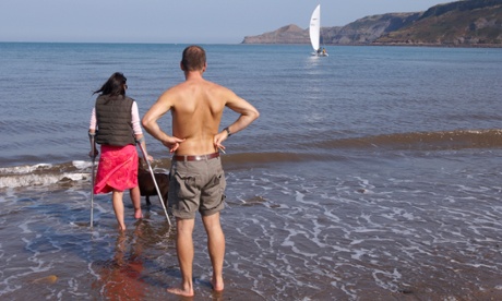couple paddling in the sea, woman on crutches