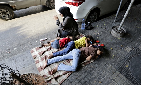 A Syrian woman sits next to her children