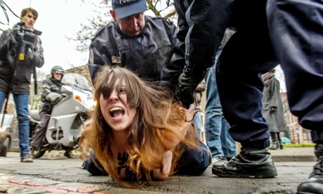 Police detain a Femen activist after she jumped in front of the car carrying Dominique Strauss-Kahn to court in Lille.