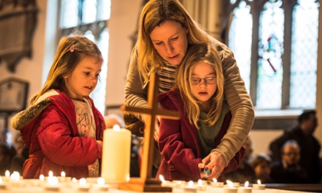 Kate Thomas helps her daughters Isabel, seven, (right) and Chloe, five, light a memorial candle at a special service at All Saints church in Weston, Bath.