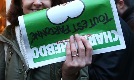 A woman holds up a copy of Charlie Hebdo magazine outside a French bookstore in London, England.
