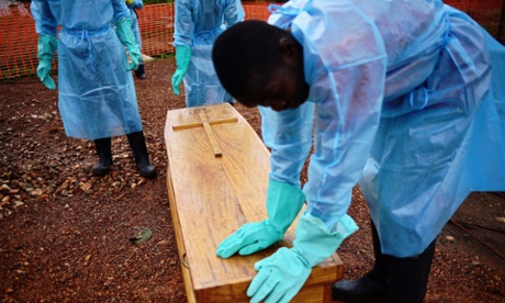 Sierra Leone burial team members in protective clothing handle the coffin of an ebola victim.