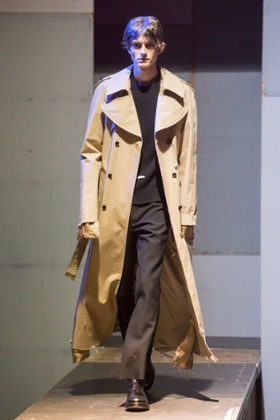 A model with hair reminiscent of Robert Peston walks the runway for Raf Simons.