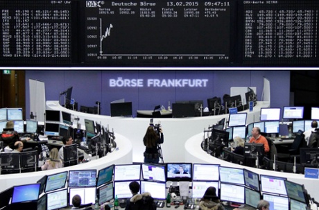 Traders are pictured at their desks in front of the DAX board.