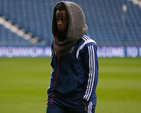 Saido Berahino walks on the pitch before the game, with something or other.