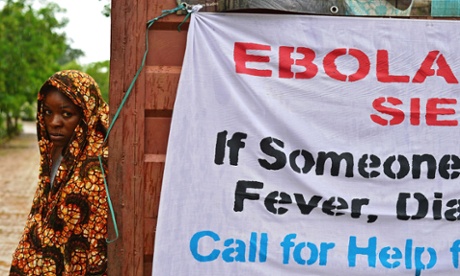 A woman stands by the gate of the government hospital under the rain in Kailahun, Sierra Leone