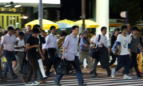 Workers cross a road at night in Tokyo, Japan.