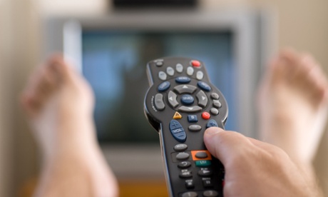Man with feet up in front of television.