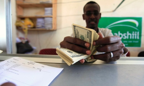 A worker counts U.S. dollars as he serve a customers at a Dahabshiil money transfer office in 