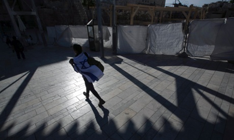 A visitor wrapped with Israel's national flag walks towards the Western Wall, Judaism's holiest prayer site, in Jerusalem's Old City