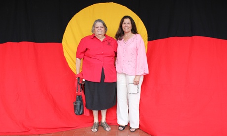 Sisters Karen Rutterman and Cynthia Briggs stand in front of the Aboriginal flag in Walgett.