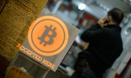 A man talks on a mobile phone in a shop displaying a bitcoin sign in Hong Kong.