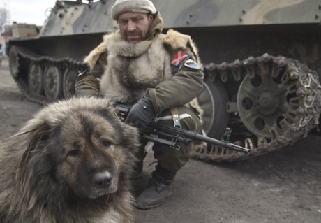 A dog sits next to a Russia-backed rebel near his tank