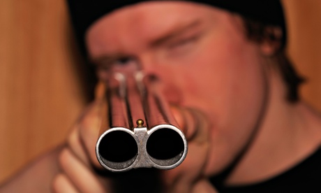 young man pointing shotgun with the end of the barrel in focus