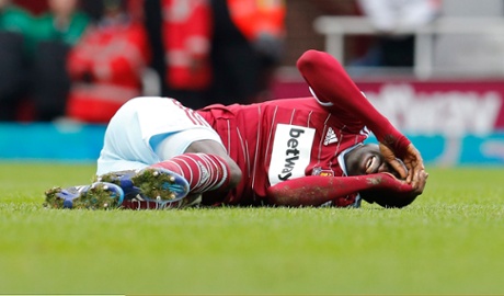 Cheikhou Kouyate lies injured after being caught.