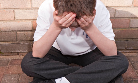 An unhappy boy outside a school