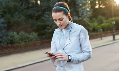 Girl checks her phone's fitness app whilst on a run