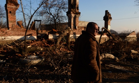 A man walks past damaged buildings in Kommunar