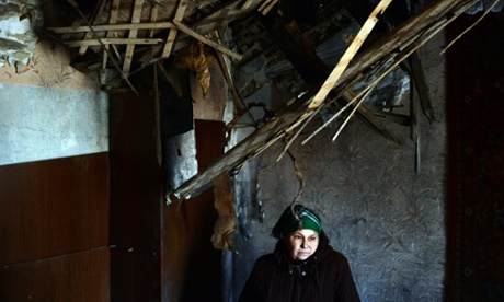 A woman stands in her damaged apartment.