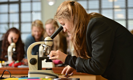 School pupils using microscopes during a science lesson in Cheltenham, Gloucestershire