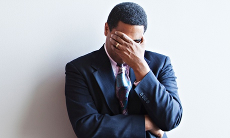 Businessman leaning against wall covering his face