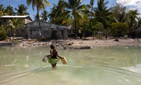 A young girl crosses the lagoon at high tide to get some water for her family, who live on a thin strip of sand that gets cut off from the main island every high tide.r