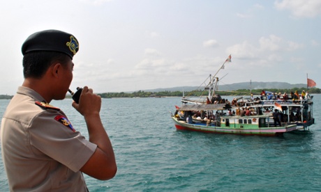 An Indonesian police officer watches a fishing boat carrying asylum seekers.