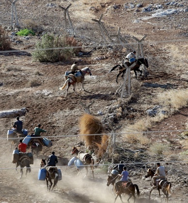 Smugglers break through the border fence as they enter Syrian territory from Turkey.