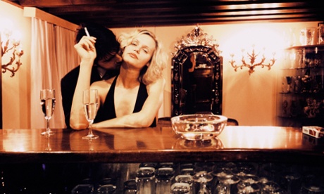 a man kissing a lady's neck while she sits at a bar