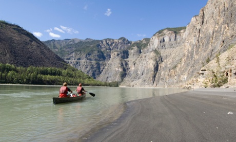 People in a canoe paddling through a canyon of the South Nahanni River, Northwest-Territories, Canada