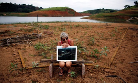 A former resident of the re-emerging old city of the Igarata, Irene De Almeida, 65, holds a photograph of the city before its was submerged in 1969, as she sits on the main street of the old city in front of Jaguari reservoir, in Igarata, Sao Paulo State, February 4, 2015.
