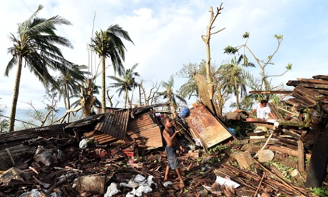 A young boy plays with a ball as his mother searches through the ruins of their family home on March 16, 2015 in Port Vila, Vanuatu. Cyclone Pam has hit South Pacific islands on Saturday with hurricane force winds, huge ocean swells and flash flooding and has caused severe damage to housing. Aid agencies say it could be one of the worst disasters ever to hit the region.