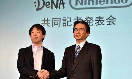 Japan's video game giant Nintendo president Satoru Iwata (R) shakes hands with Japanese online game operator DeNA president Isao Moriyasu