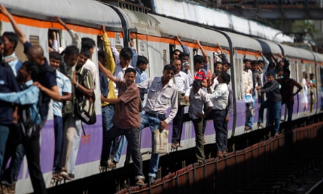 Commuters hang on the outside of a local train in Mumbai. According to some estimates, more than 5,000 people can cram into carriages designed to carry no more than 1,700.