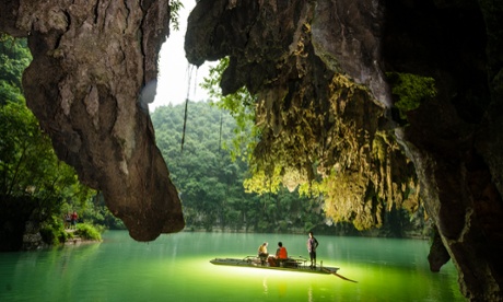 A boatman guides tourists down the Poxin river as it emerges from underground.