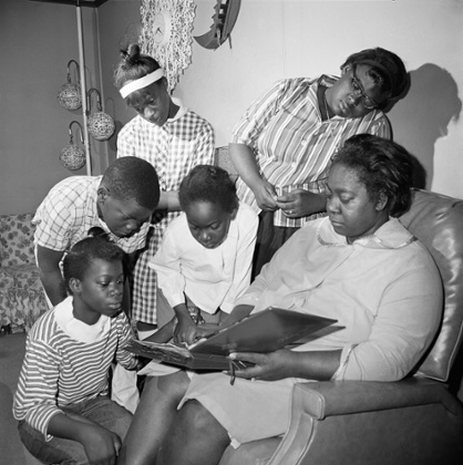 Exerlena Jackson, widow of Wharlest Jackson, ex-treasurer of the Natchez NAACP, who was killed by a bomb blast in his pickup truck, is shown with her family. Front left to right are: Denise and Delresia. In back, left to right are: Wharlest Jr, Doris and Deborah. They are looking at a photo album of the last pictures taken of the six together in Natchez, Mississippi, on 28 February 1967.