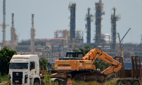 A truck carries construction machinery near the refinery and processing plant