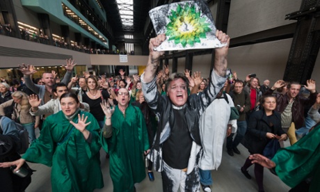 Reverend Billy leads the congregation out of Tate Modern holding up an oil-soaked BP logo. -- The Reverend Billy performed at Tate Modern today, urging an end to extraction of oil for the Tar Sands and of arts sponsorship by BP, which gives a company engaged in this most polluting activity a false green image. London, UK. 18th July 2011