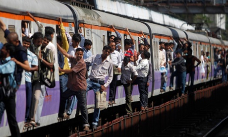 Commuters hang on the outside of a local train in Mumbai.