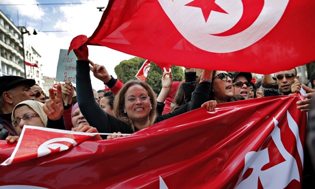 People hold Tunisian flags as they demonstrate two days after gunmen attacked the Bardo museum 