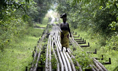 A woman walks along an oil pipeline in Warri, Nigeria