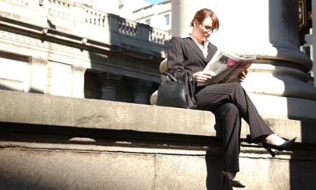 Woman reading newspaper in the city, London.